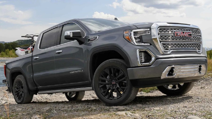 A gray GMC Sierra 1500 pickup truck drives up a rocky terrain.