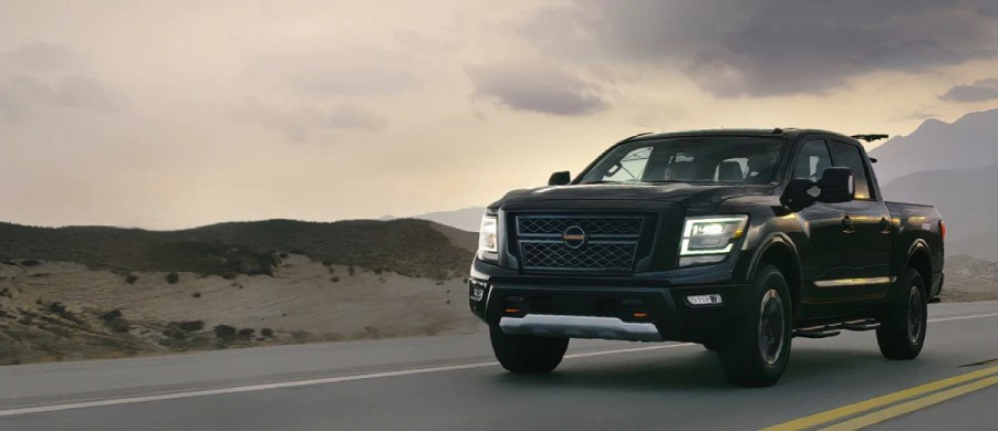 A black Nissan Titan driving down a highway.