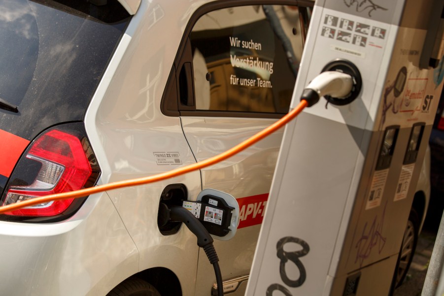 An electric car stands at a charging station to recharge for full range, which is not the same as mpge