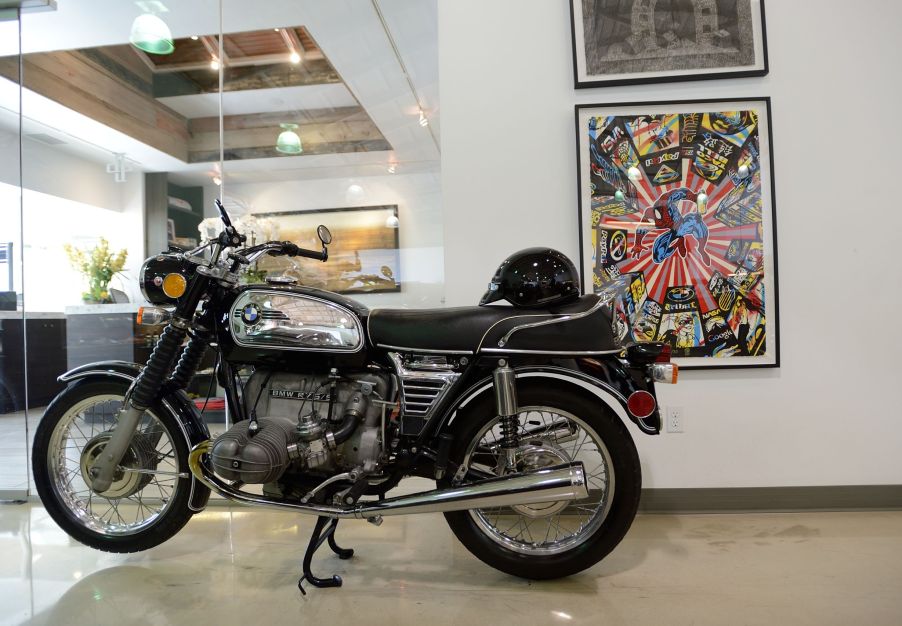 The side view of a black-and-chrome 1970 BMW R75/5 on its center stand in an office building