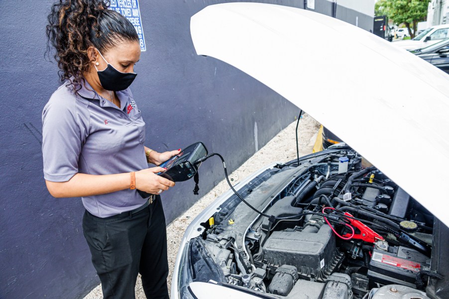 This is a photo of an automotive technician at an auto parts store testing a car battery and the vehicle's entire electrical system. You can change a car battery by yourself, but its wise to enlist professional help to make certain your battery needs to be changes. | Jeffrey Greenberg/Education Images/Universal Images Group via Getty Images