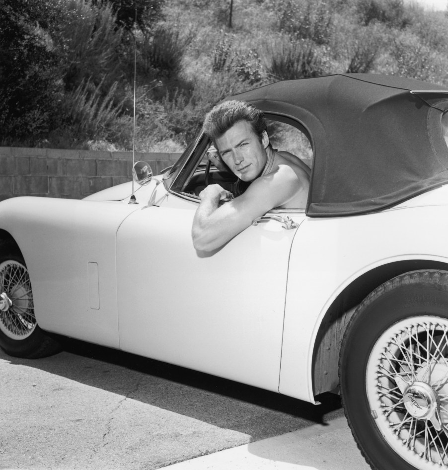 Clint Eastwood poses shirtless in his Jaguar convertible. Traffic laws do not dictate drivers' outfits. Penal laws do. Driving shirtless is not illegal wherever being shirtless in public is legal. Drivers are not exempt from public decency and indecent exposure laws. | Hulton Archive/Getty Images