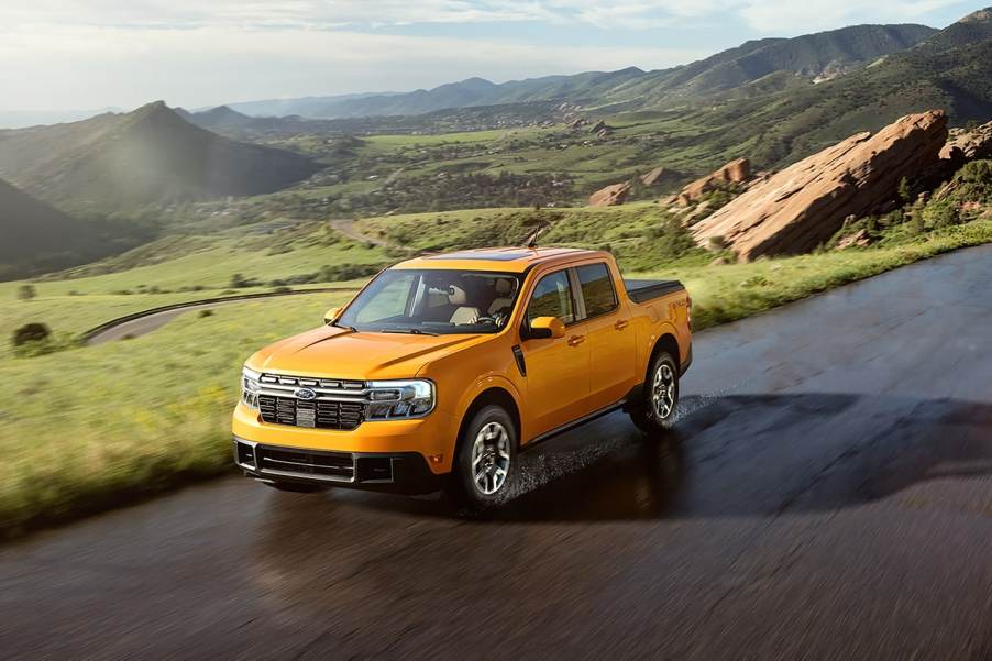 Orange 2022 Ford Maverick compact pickup truck driving on a mountainous road, its newly announced fuel economy rating is superb.