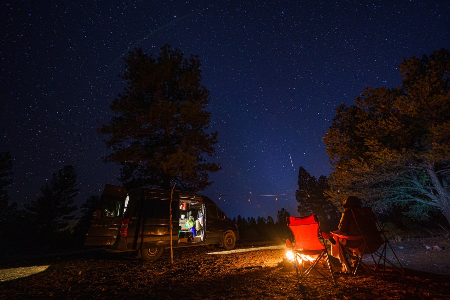 A sprinter van camps outside by a fire