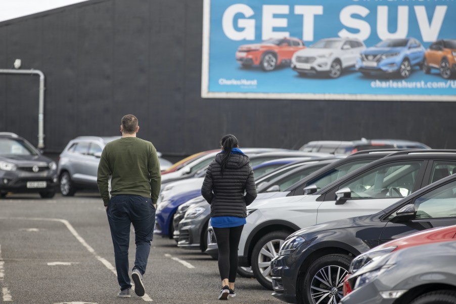 Potential customers walk around a car lot