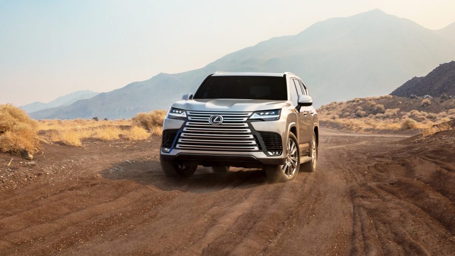 A silver Lexus LX 600 on a dirt back road shot from the front 3/4