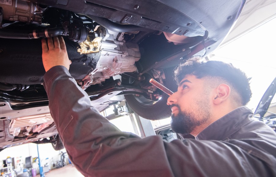 A mechanic checks underneath a car