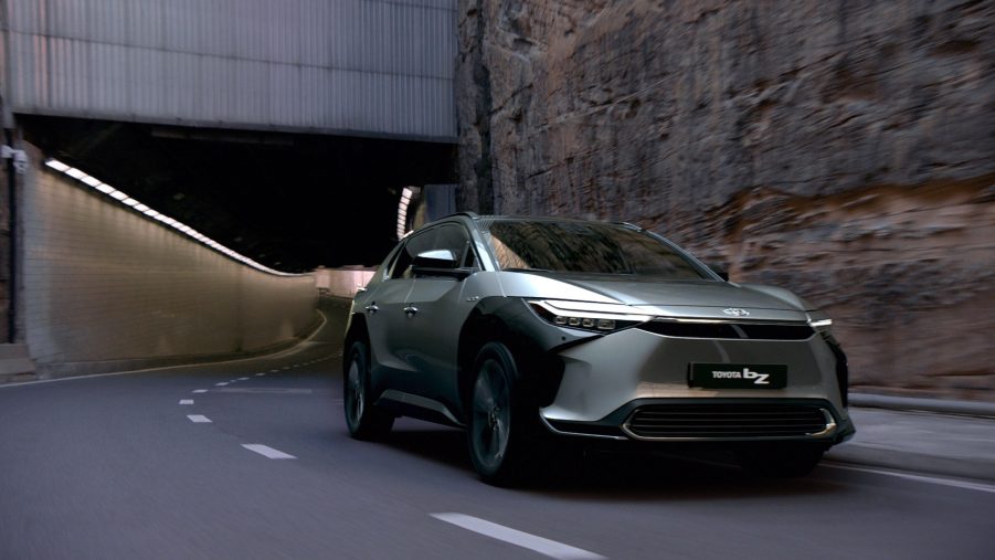 Gray 2022 Toyota bZ4X EV driving by a large wall