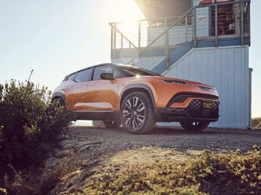 Orange 2023 Fisker Ocean electric crossover SUV parked in front of a lifeguard tower