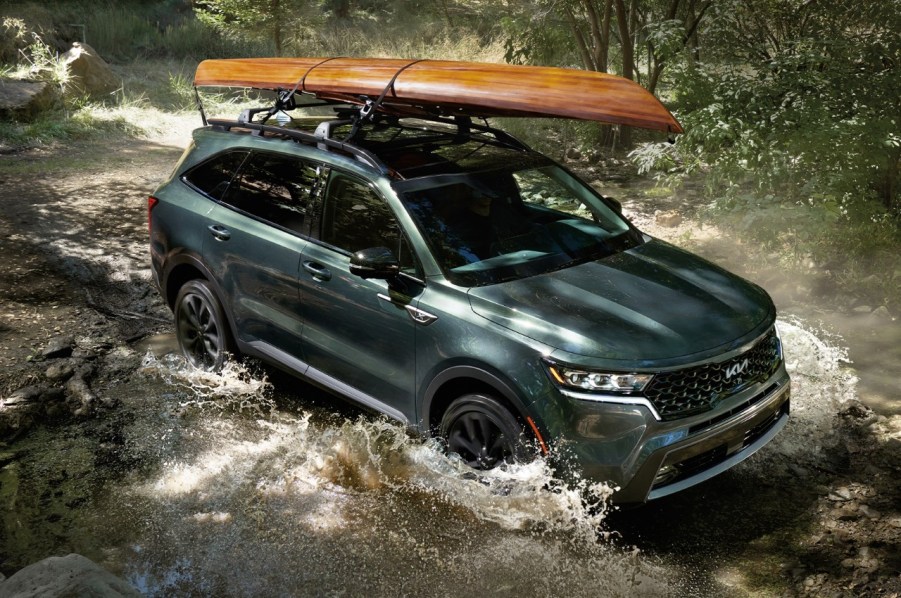 A dark green 2022 Kia Sorento splashing across a river.