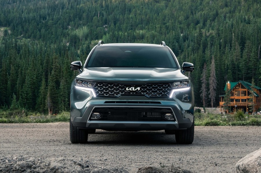 A dark colored 2022 Kia Sorento in front of a log cabin.