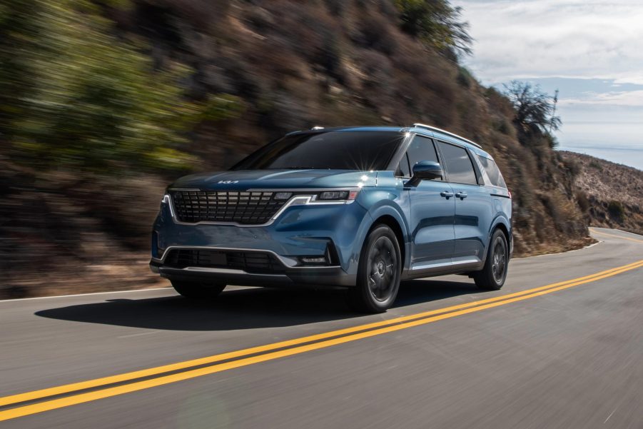 A blue 2022 Kia Carnival minivan driving on a road, it's been recalled