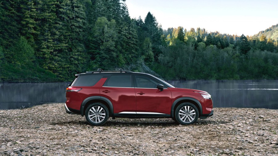 A red 2022 Nissan Pathfinder three-row SUVparked near a body of water