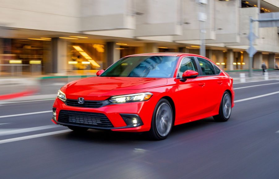 Rallye Red 2022 Honda Civic driving by a large modern building