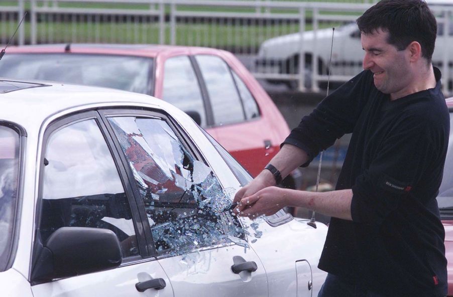 A demonstration of a thief breaking into a car by a police officer and a decoy car in Harlow, Essex, England