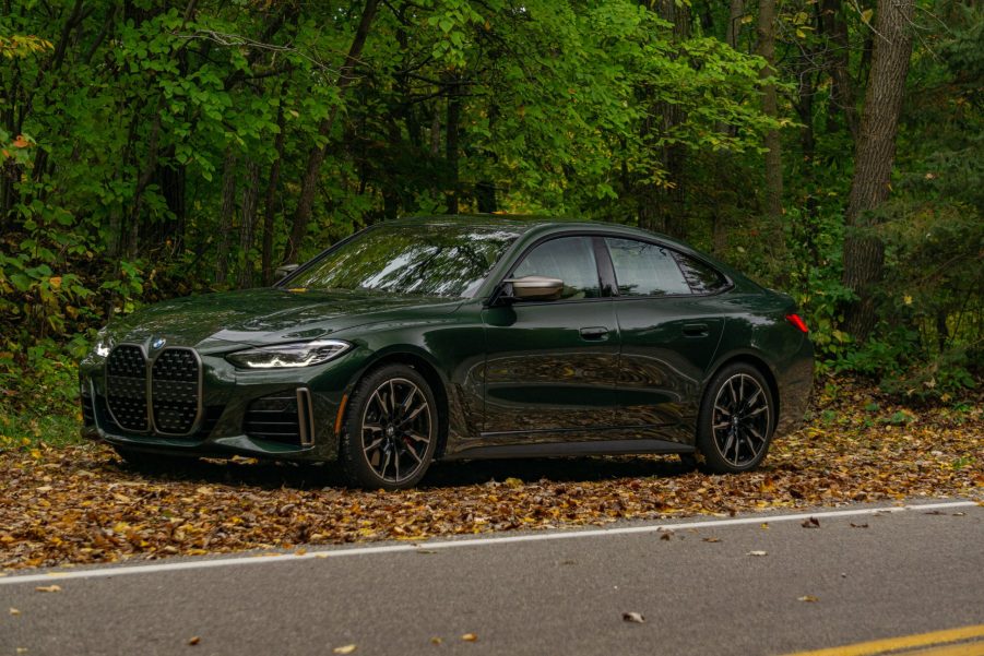 The front 3/4 view of a green 2022 BMW M440i xDrive Gran Coupe in a forest