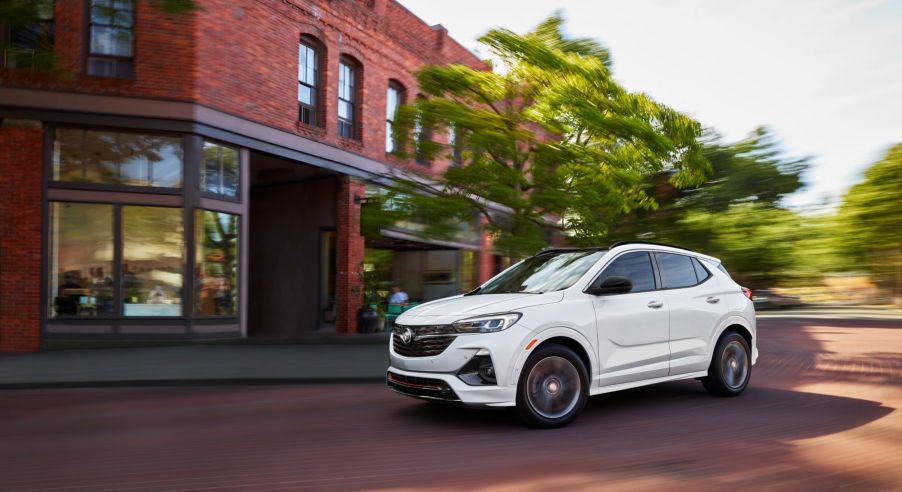 The 2022 Buick Encore GX compact crossover SUV with a white paint color option driving on a cobblestone road