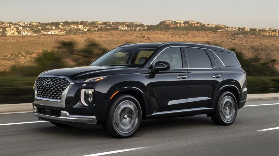 A black 2022Hyundai Palisade driving down a road.