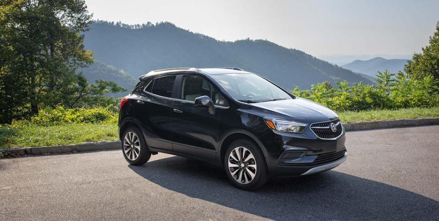 A dark colored Buick Encore with a moutntain behind.