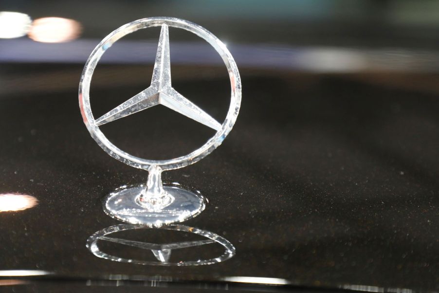 Silver standing Mercedes-Benz logo on top of a black car.