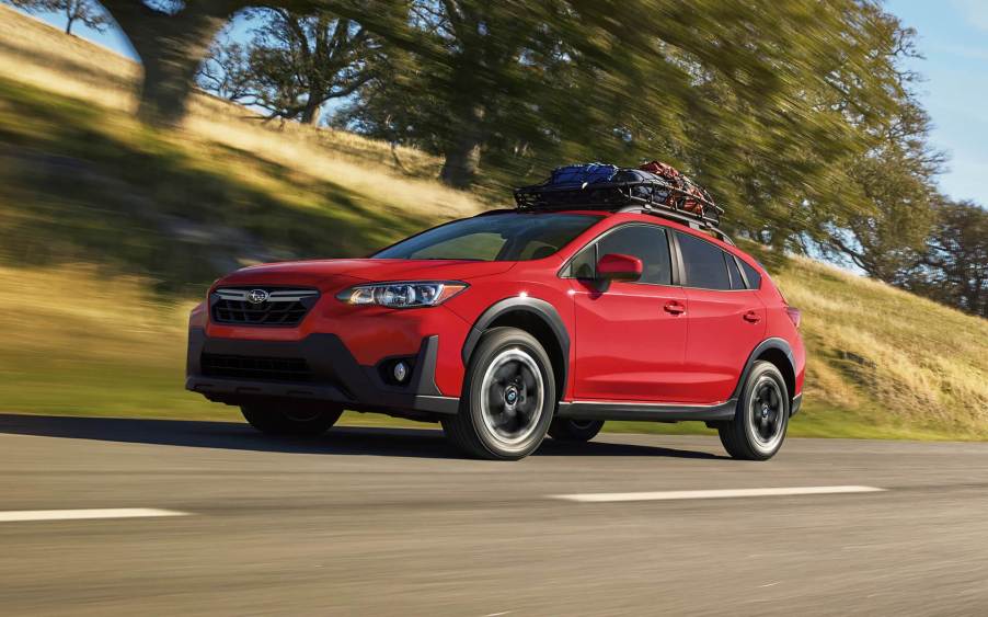 Pure Red 2022 Subaru Crosstrek driving by a hill