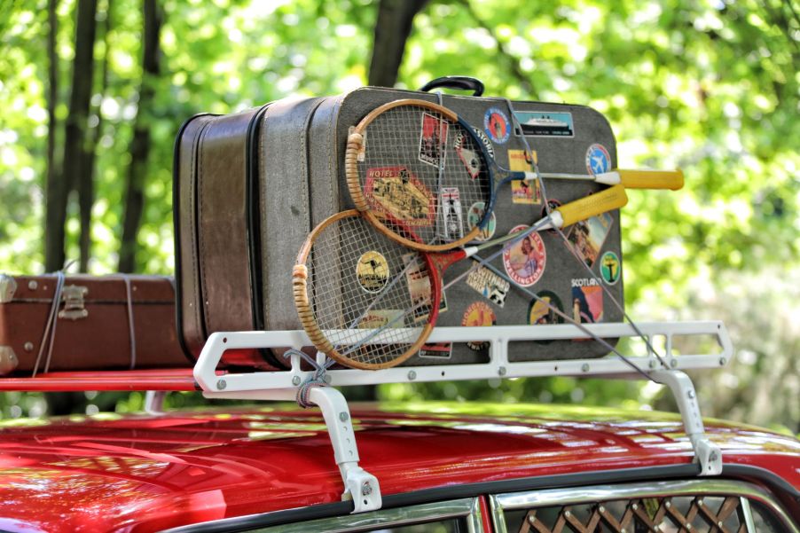 Luggage on roof racks on a red vehicle.