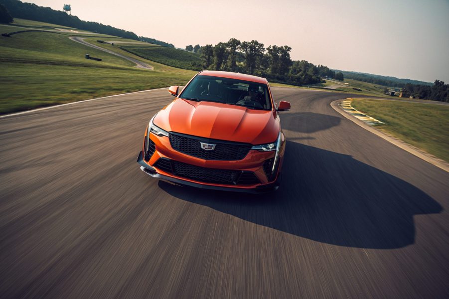 A front view of an orange 2022 Cadillac CT4-V Blackwing exiting a corner at a race track.