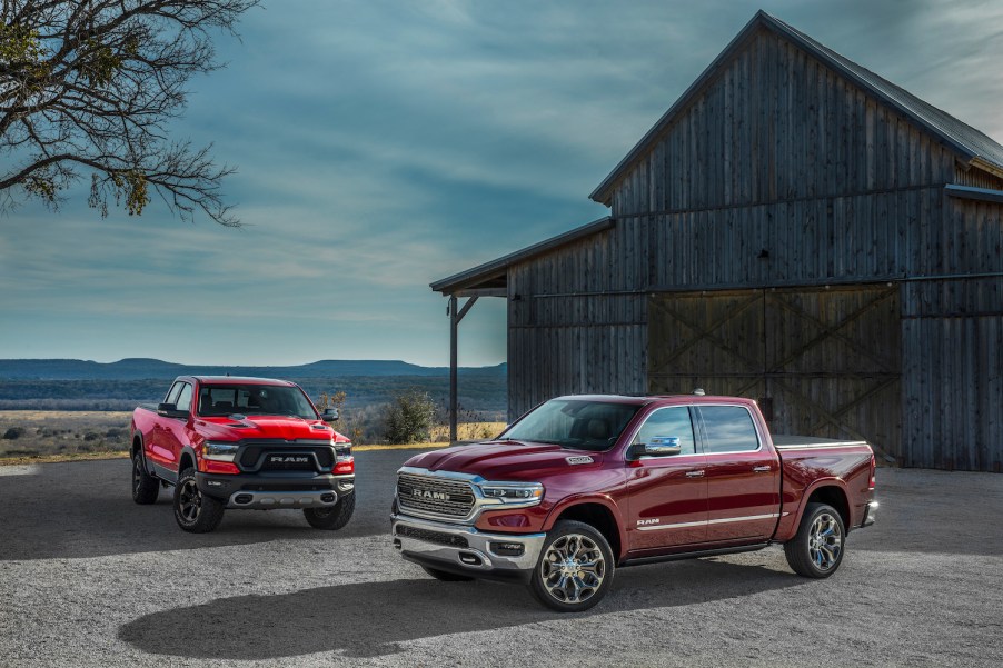 Promo shot of two red Ram 1500 trucks parked in front of an old barn.