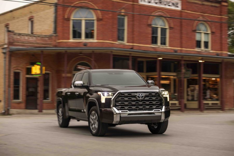 A brown Toyota Tundra 1794 Edition pickup truck driving in front of a brick building