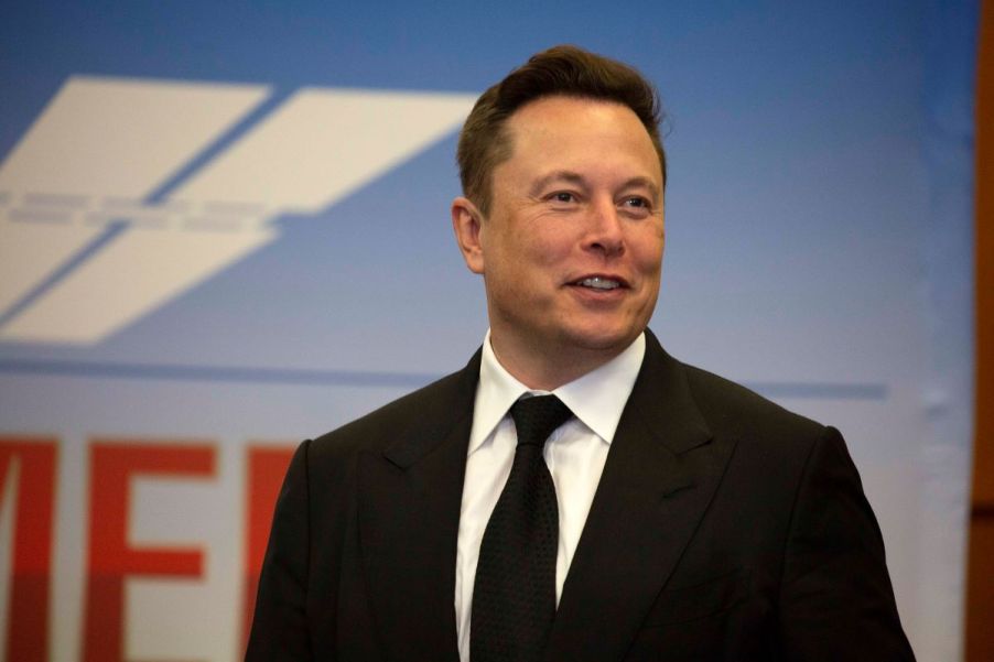 Elon Musk, CEO of Tesla, with Tesla's Subpoena, wearing a black suit with a black tie.