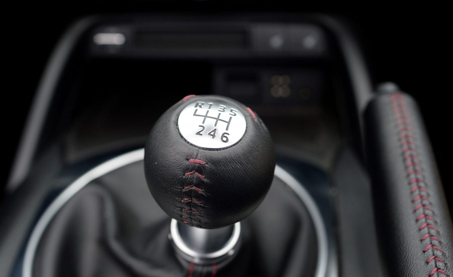 A black gear select from a manual transmission versus an automatic transmission with a silver plate.