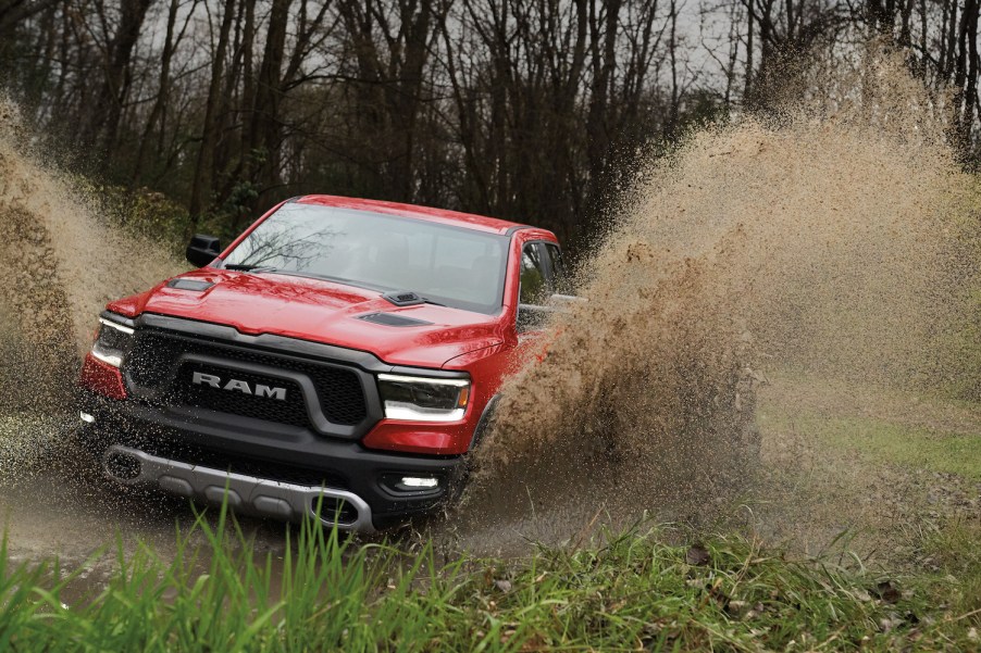 Red pickup truck driving through a swamp, fishtails of water erupting from each wheel well.