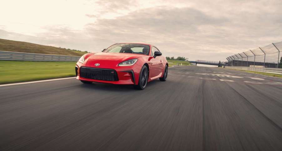 Red 2022 Toyota GR86 sports car driving along a track, toward the camera