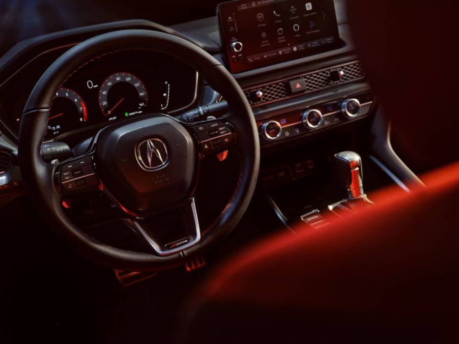 View of the cockpit and dashboard of the 2023 Acura Integra; steering wheel, dials, and CVT shifter