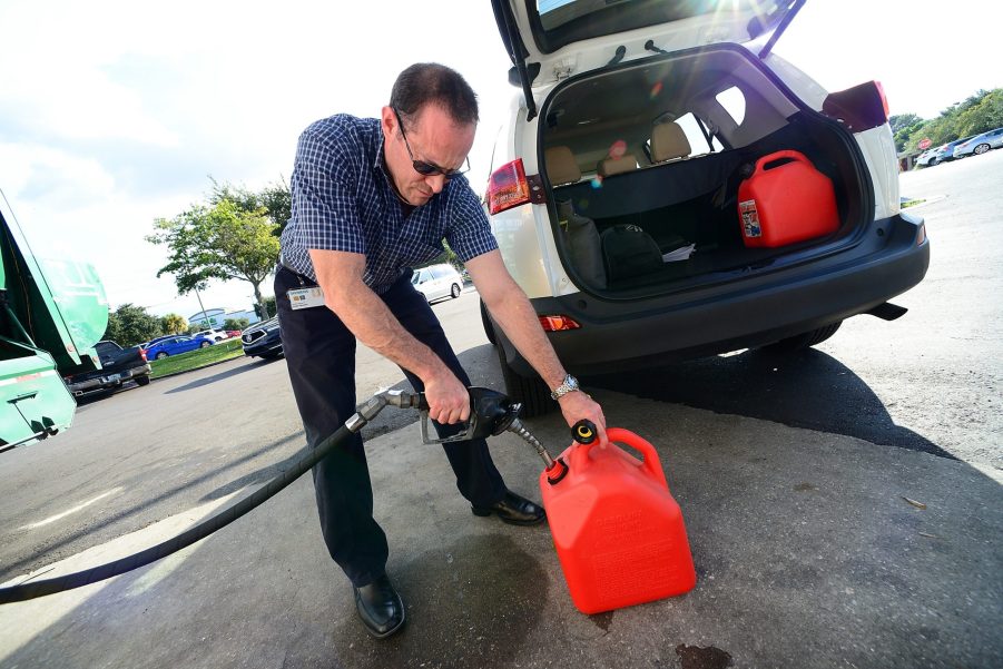 A Florida resident safely fills gas cans at a station away from their white SUV