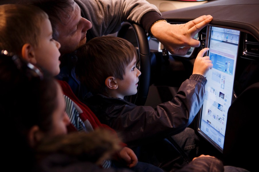 Child playing with a Tesla's 17-inch touchscreen in a dealership.