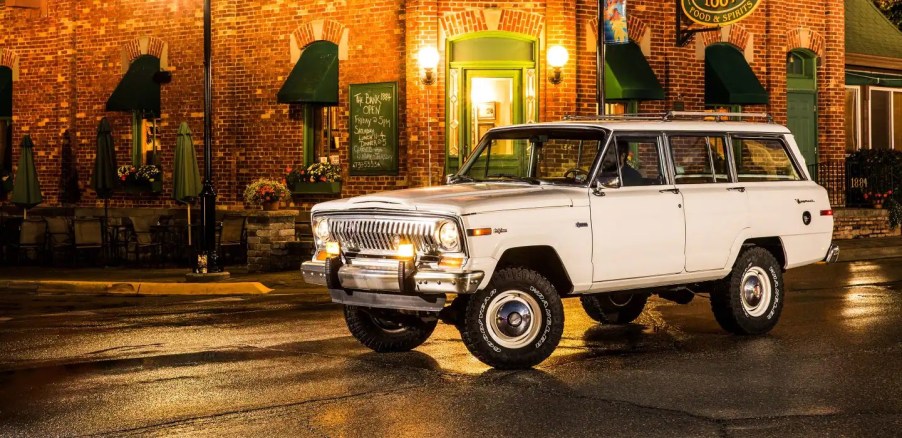 A white 1963 Jeep Wagoneer against a city.