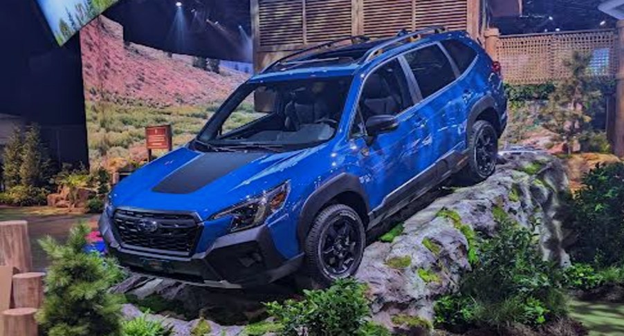 A blue Subaru Forster Wilderness off-road SUV is on a rock at the 2022 New York International Auto Show.