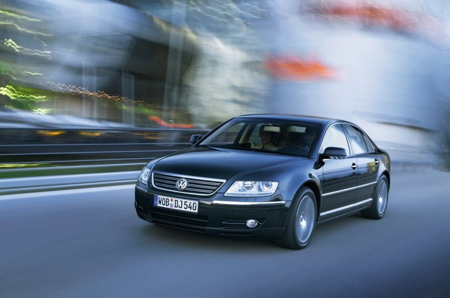 A black Volkswagen Phaeton, a 200 MPH performance luxury sedan, flies down a city street.