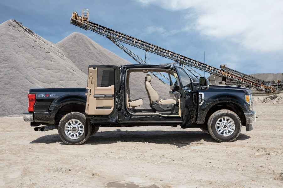 Black Ford Super Duty pickup truck parked on a jobsite with all four of its supercab doors open.