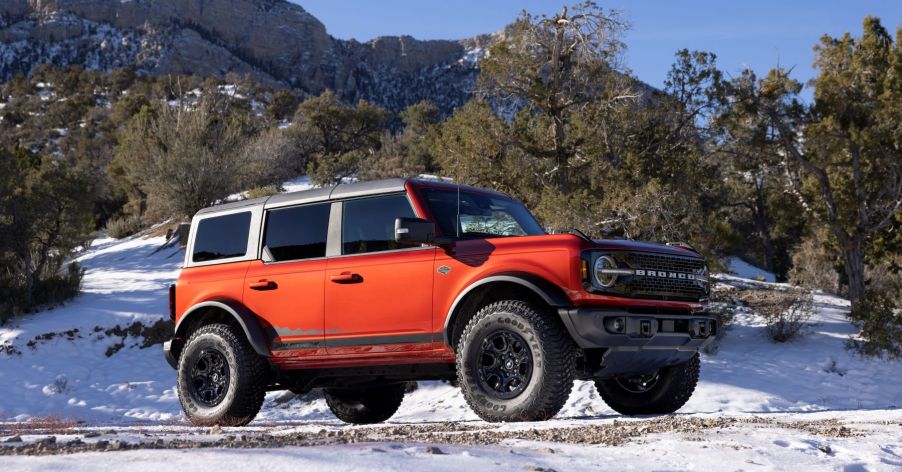 A red 2022 Ford Bronco Wildtrak model with option HOSS 3.0 parked on a snowy off-road trail in a forest