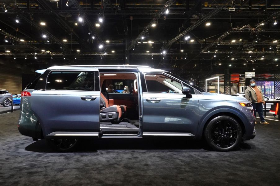 A light blue 2022 Kia Carnival with the back door open.