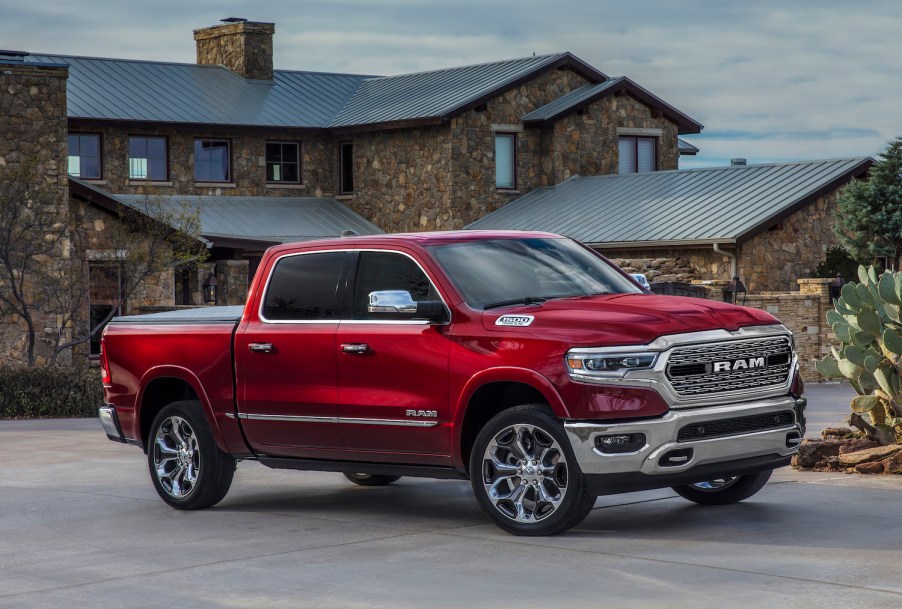 Red Ram pickup truck parked in front of a stone house.