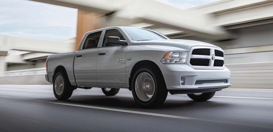 A white 2022 Ram 1500 Classic drives on an urban road.