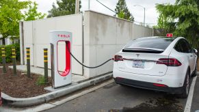 A white Tesla Model X charging at a supercharger EV charging station