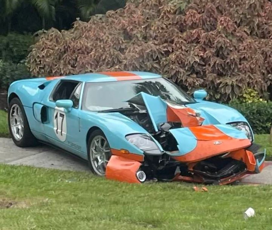 The Florida Ford GT crash. A crashed 2006 Ford GT Heritage Edition car is splayed out on the sidewalk near a stand of palm trees as passersby take pictures