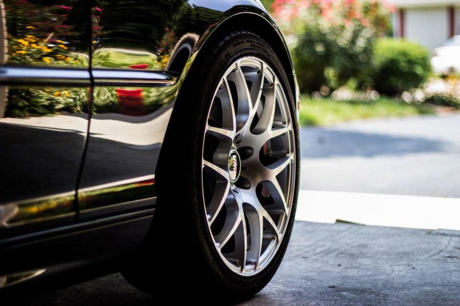 Black sedan with grey and silver wheels. A portable air compressor can quickly fill saggy tires.