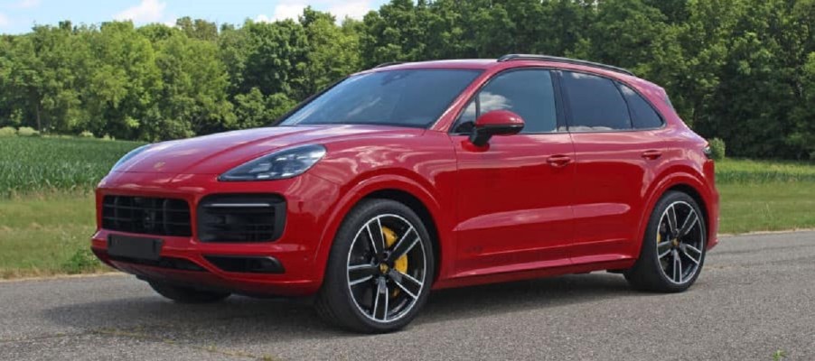 A red 2022 Porsche Cayenne in front of trees.