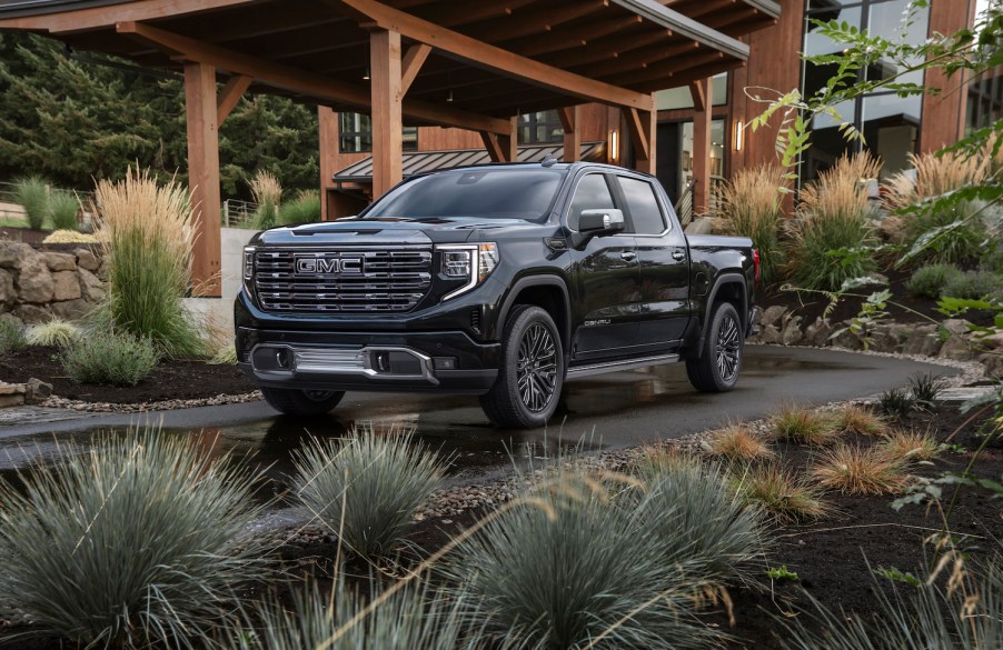 A promo shot of a black GMC Sierra pickup truck parked in a driveway.