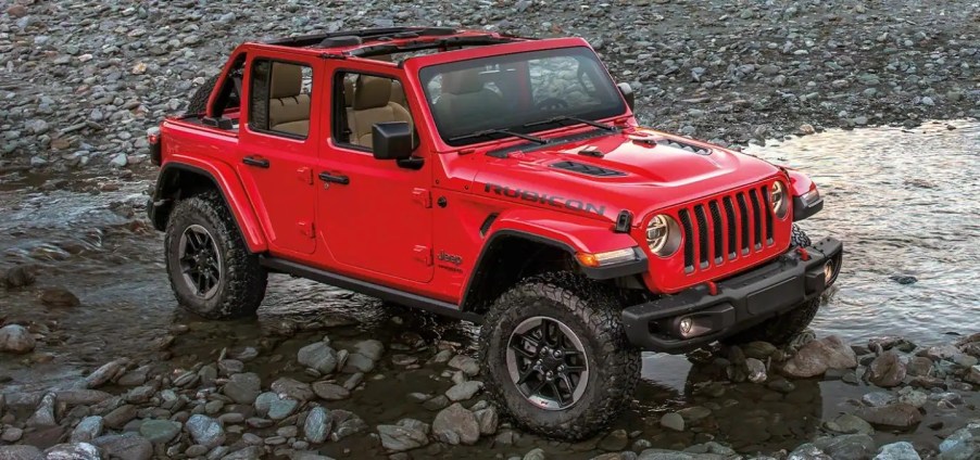 A red 2022 Jeep Wrangler splashing into a lake.